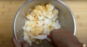 Mixing rice in a metal bowl with a spatula, creating an even blend of flavors.